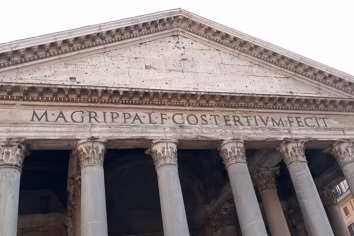 Close-up of the Pantheon's ancient facade in Rome, featuring prominently engraved Latin inscriptions above the columns.
