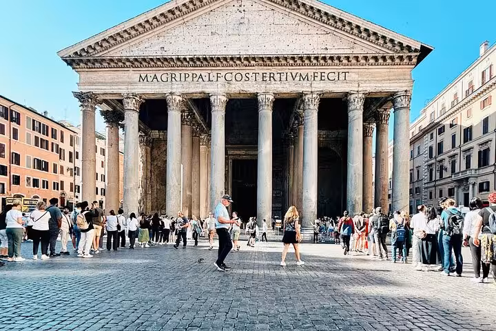 People queue at the Pantheon entrance in Rome, capturing its majestic columns and bustling atmosphere.