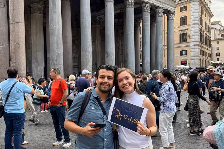 Visitors pose happily in front of the majestic Pantheon columns in Rome, capturing a memorable travel experience.
