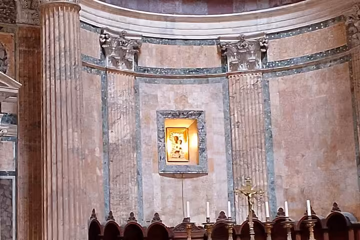 The Pantheon's grand interior features majestic columns and a glowing religious icon, part of Rome's historic architecture tour.