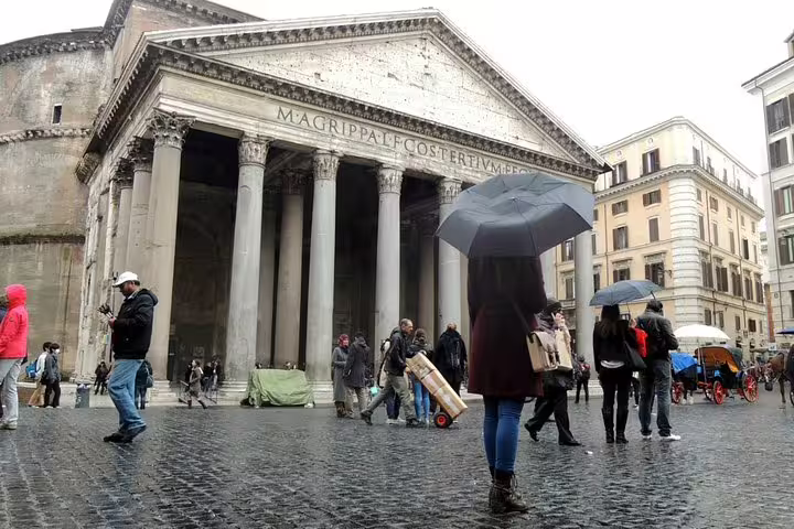 Tourists with umbrellas walking in the rain near the Pantheon in Rome