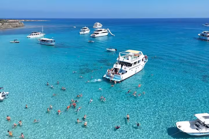 Boat with slide at Akamas Blue Lagoon, Cyprus, with snorkeling swimmers on Paphos bus and boat transfer