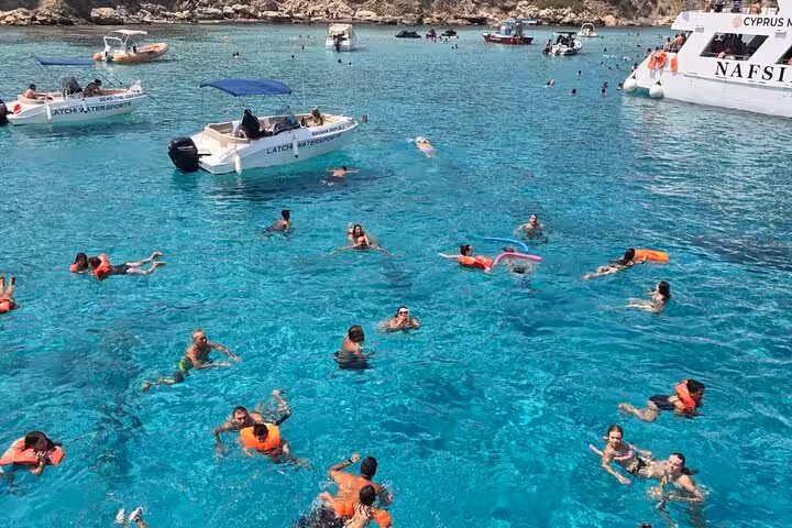 Swimmers in crystal-clear Blue Lagoon Akamas, Paphos boat transfer stop with snorkelling and slide fun