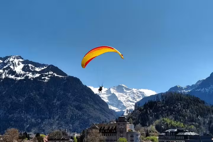 Paraglider soaring over the Swiss Alps with stunning views of snow-capped peaks on a Jungfraujoch adventure.