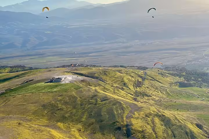 Paragliding adventure above the lush green hills of Agafay Desert with panoramic views of Marrakech.