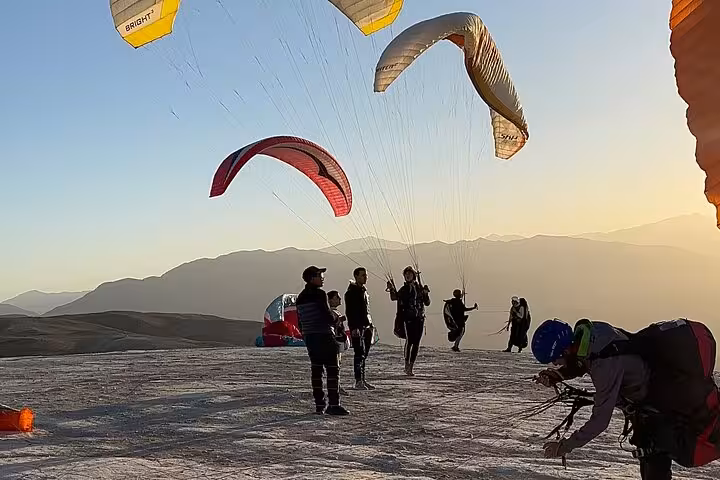 Paragliders preparing for takeoff at sunset in the scenic Agafay Desert near Marrakech, showcasing adventure and travel.