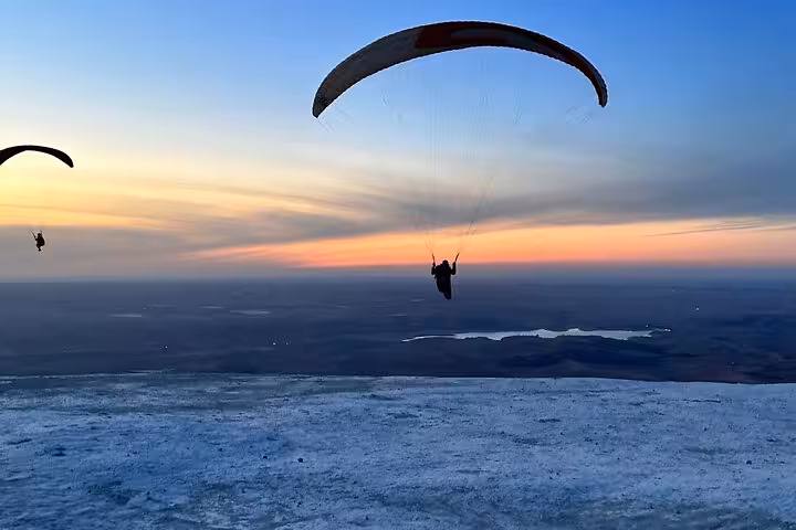Paragliders soar against a stunning Agafay Desert sunset in Marrakech, highlighting an exhilarating adventure experience.