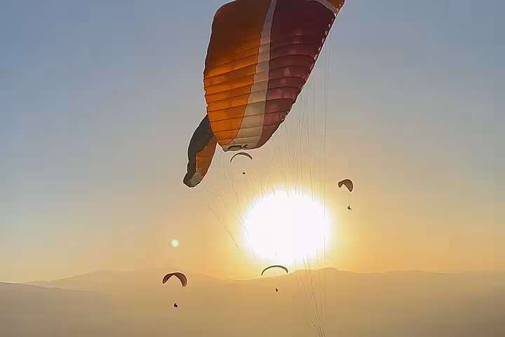 Paragliders soaring against a stunning sunset in the Agafay Desert, offering an exhilarating Marrakech adventure experience.