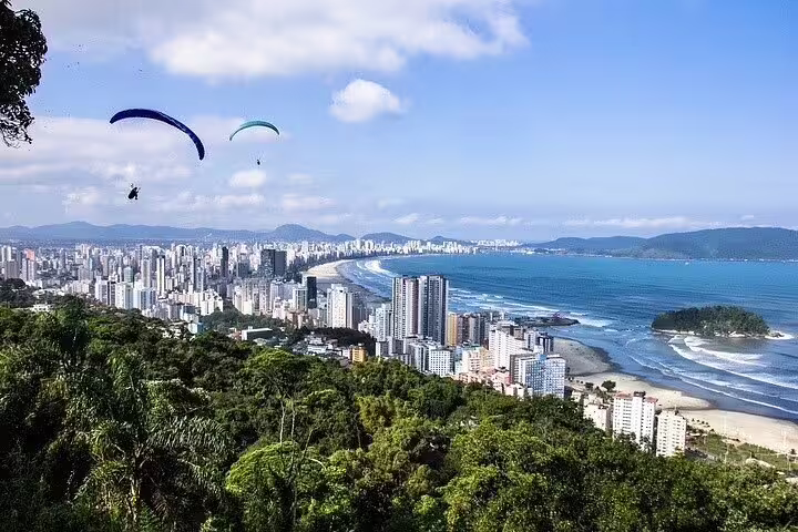 Paragliders soar above Santos coastline offering breathtaking views of the city and ocean on a shared full-day tour.
