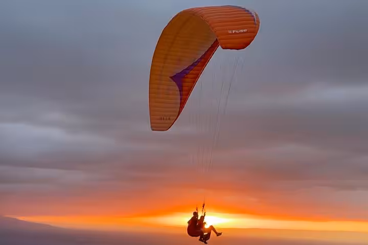 Person paragliding at sunset over Agafay Desert, capturing the beauty of Marrakech adventure tourism.