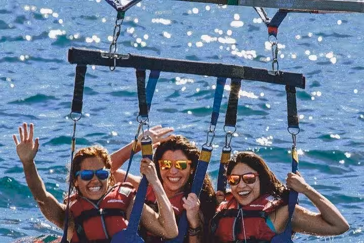 Smiling friends in tandem parasailing harness above Red Sea, Hurghada Sahl Hasheesh Makadi Bay adventure