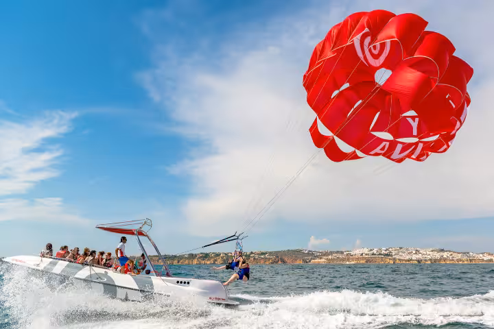 Thrilling parasailing adventure over Albufeira with a red parachute and speedboat along the stunning Algarve coast