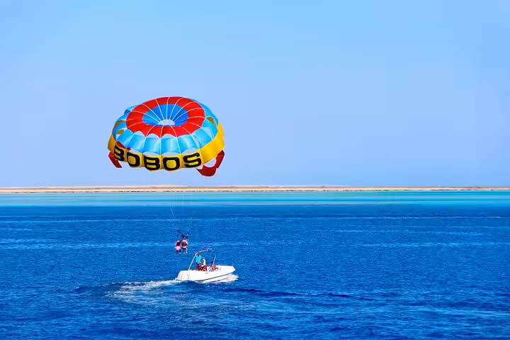 Parasailing over the Red Sea in Hurghada, speedboat below on a sunny Egypt coastal adventure