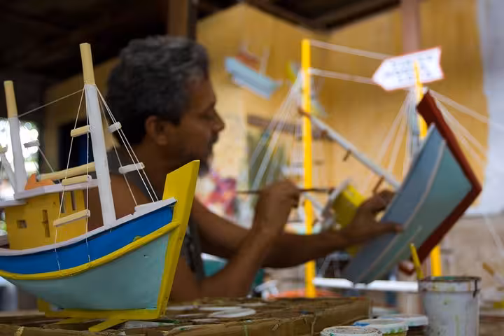 Artisan painting model boats in a vibrant workshop during a Paraty historical center tour by Paraty Tours.