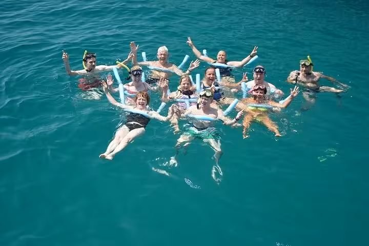 Group of happy tourists snorkeling and floating in clear water, enjoying a fun Paraty boat tour experience.