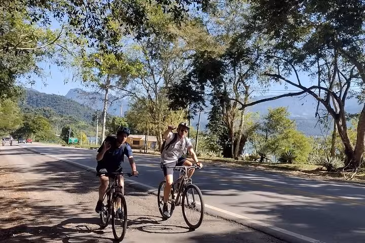 Cyclists enjoying a sunny ride along the scenic road in Paraty during a 2-hour guided bike tour.