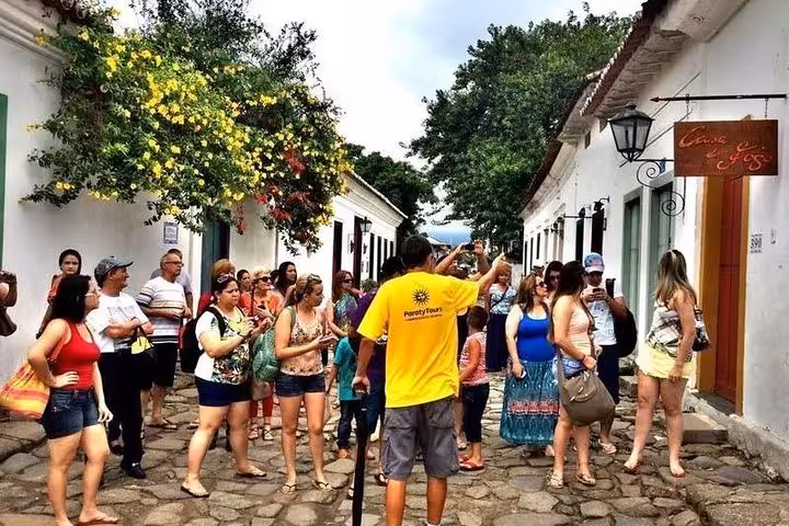 A lively group gathers around a guide in Paraty's historic center for a cultural walking tour with Paraty Tours.