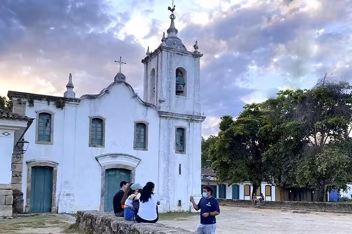 Tourists gather near a historic church in Paraty, Brazil, capturing memories during a cultural and historical tour.