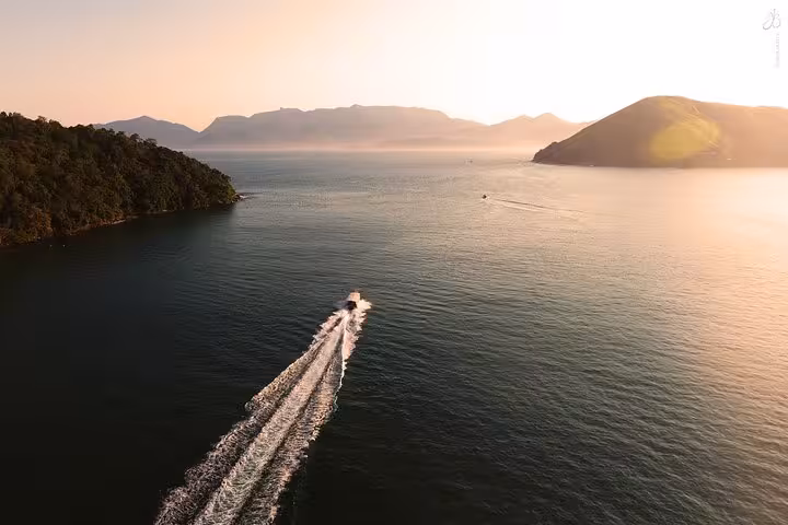 Aerial view of a boat cruising towards Ilha Grande at sunset, showcasing scenic ocean and island landscapes.