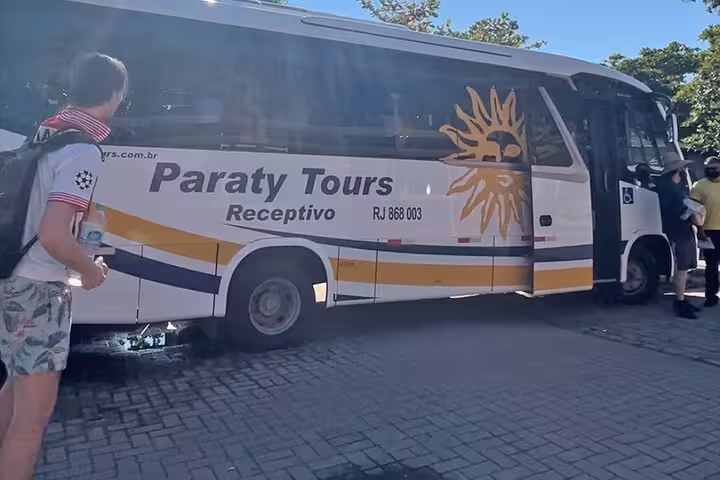 Paraty Tours bus parked, ready for a shared transfer from Paraty to Ilha Grande, with passengers boarding.