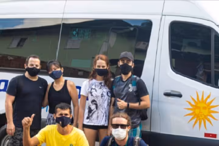 Group of travelers in masks preparing for shared transfer from Paraty to Ilha Grande with a comfortable van.