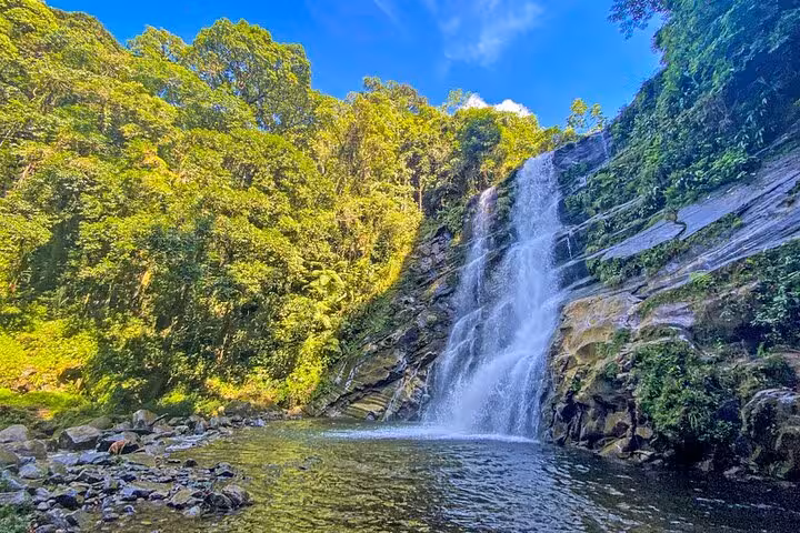 Stunning view of Melancia Waterfall cascading into a clear pool surrounded by lush greenery in Paraty.