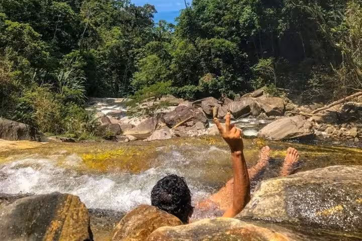 Enjoy a thrilling slide down natural rock formations at Melancia Waterfall, surrounded by lush Paraty rainforest.