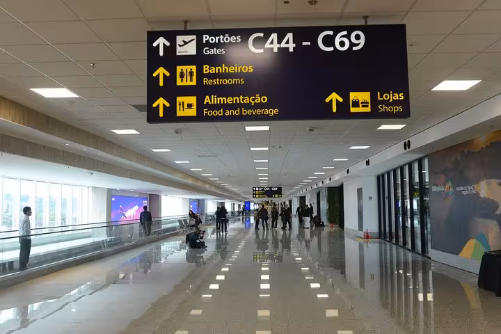 Spacious airport corridor in Rio de Janeiro showing directions to gates, restrooms, and shops for travelers.