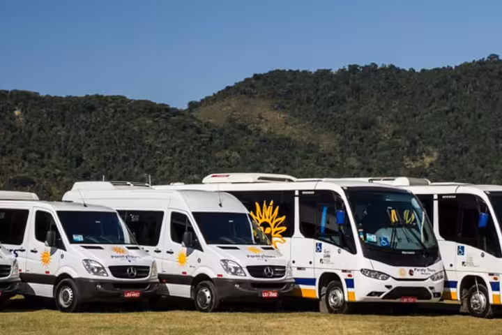 Fleet of modern shuttle vehicles set against a scenic mountain backdrop for Paraty to São Paulo shared transfers.