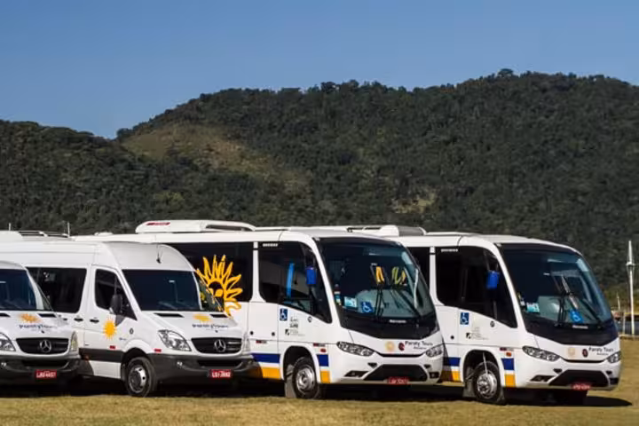 Paraty Tours buses and vans parked with lush hills in the background, offering shared transfers to Rio de Janeiro.