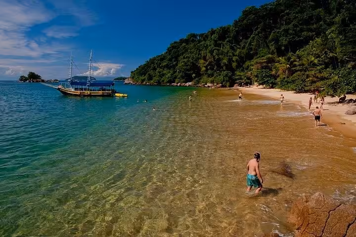 Crystal clear waters and a yellow boat near a tropical beach, highlighting the Paraty Tours boat tour experience.