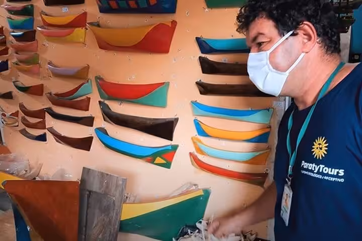 Guide from Paraty Tours showcasing vibrant boat models in a local artisan shop during a historical center tour.