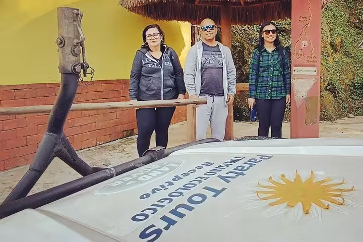 Group of tourists posing beside a Paraty Tours jeep, ready for an adventurous exploration of scenic landscapes.