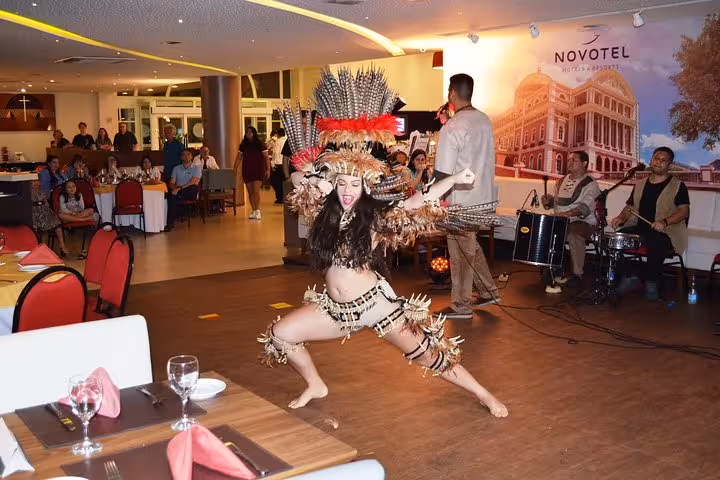 Folklore themed dinner show with dancer in feather headdress performing on stage beside live band and guests