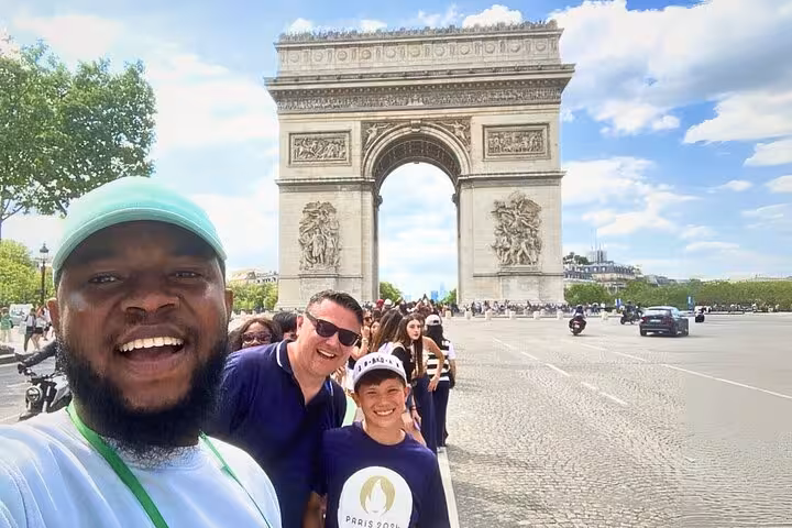 Travelers posing by Arc de Triomphe on a private Paris tour with Champs-Élysées stroll and macaron tasting