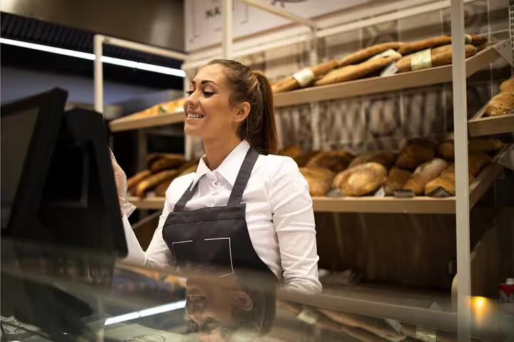 Friendly bakery staff in Paris offering fresh bread delights on gourmet tour.