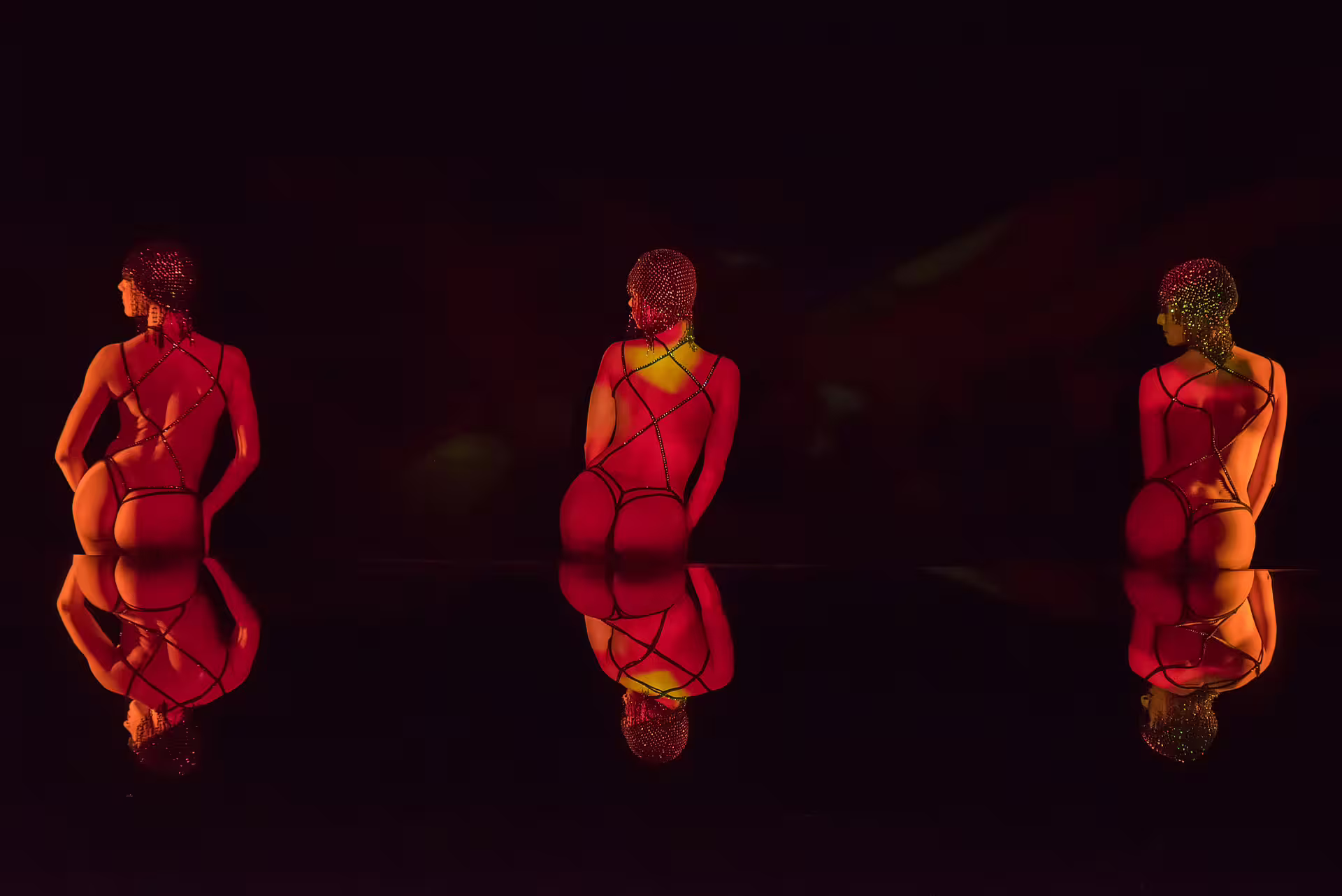 Three performers in jeweled bodysuits under red stage lighting at Paris cabaret show