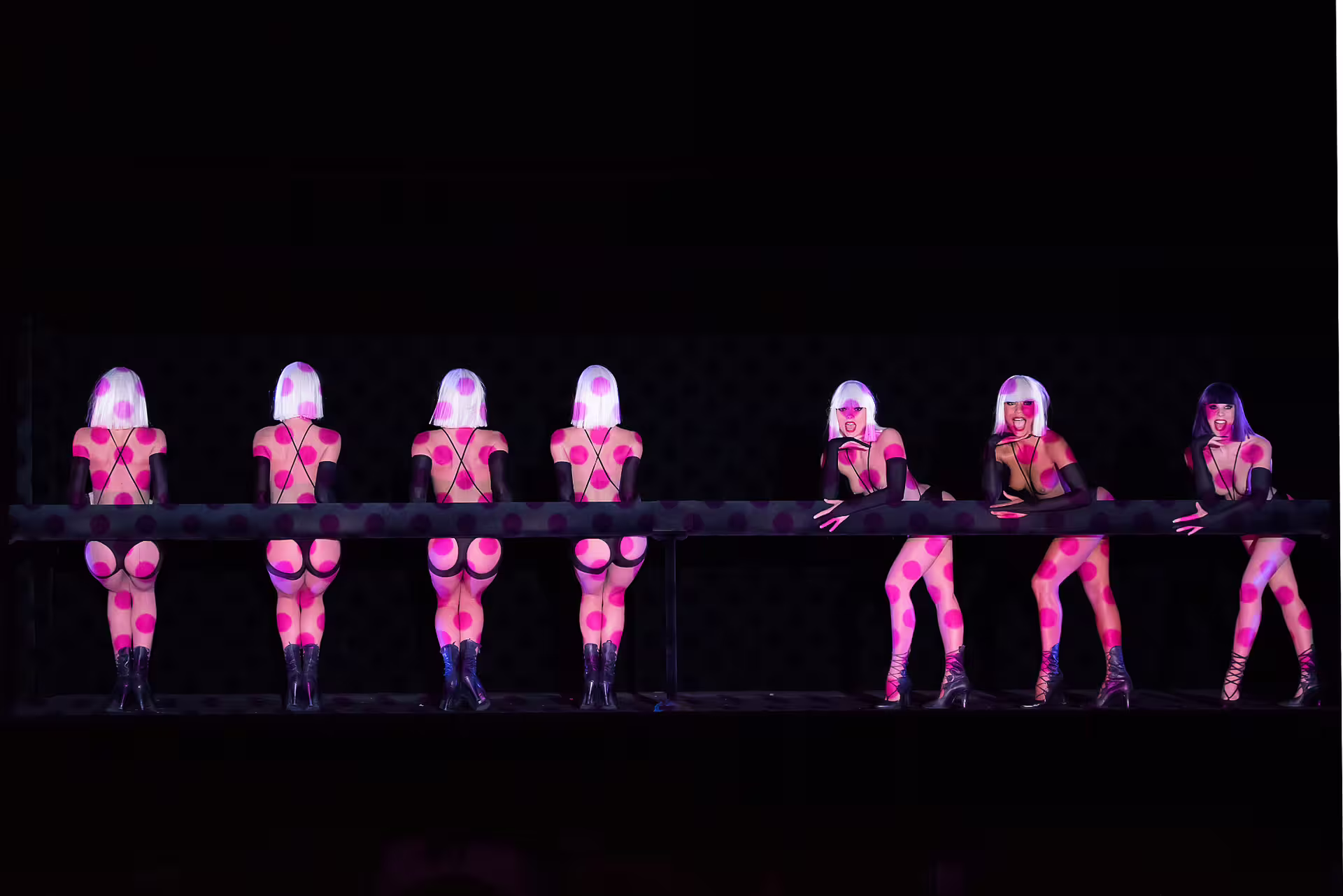 Cabaret dancers in pink polka dot costumes and white wigs performing on Paris stage