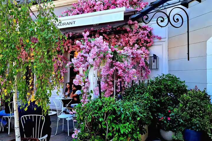 Paris café terrace with pink blossoms, ideal stop before private round-trip transfer to La Vallée Village