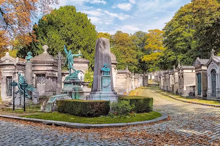 Cobblestone lane with ornate mausoleums and statues in Paris cemetery, graves of the famous private guided walk