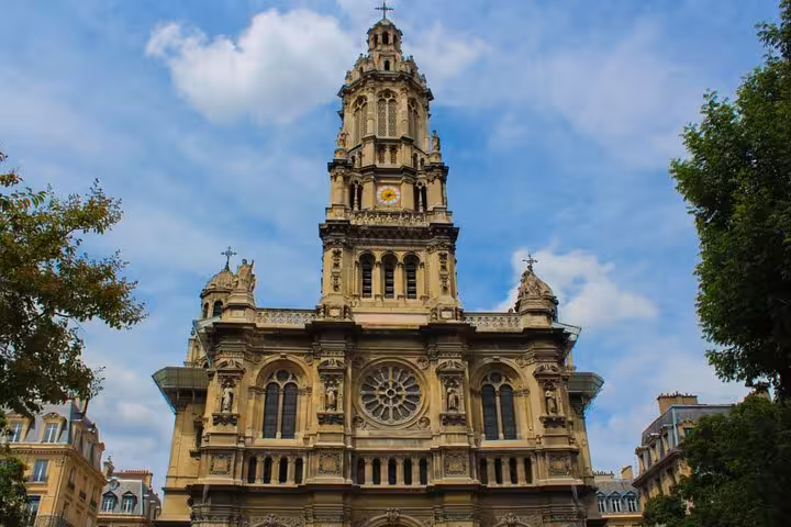 Ornate French Neo-Baroque church facade with tall bell tower and rose window in Paris