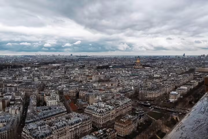Panoramic aerial view of Paris rooftops and cityscape from Eiffel Tower top floor on cloudy day
