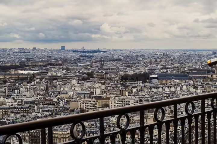 Panoramic view of Paris cityscape from Eiffel Tower top floor observation deck with iron railing
