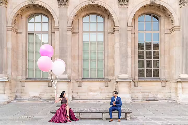 Couple sitting on bench with pink balloons during professional Paris photoshoot at the Louvre