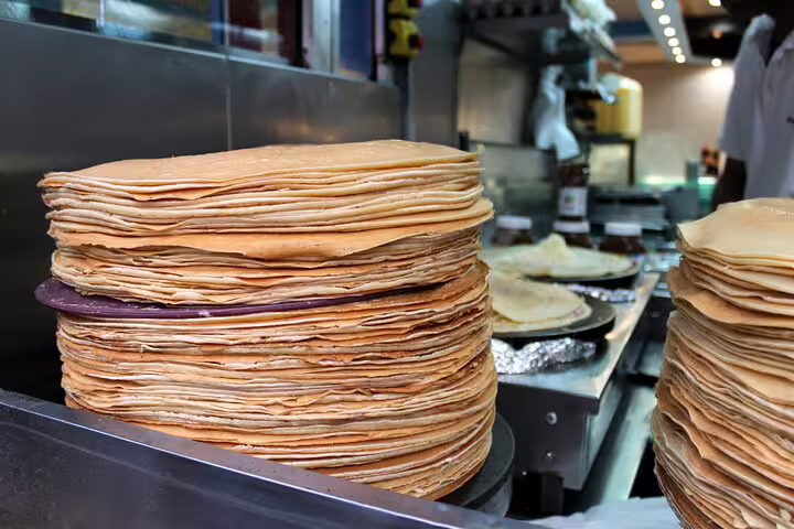 Large stacks of freshly made golden crepes at a Paris creperie counter
