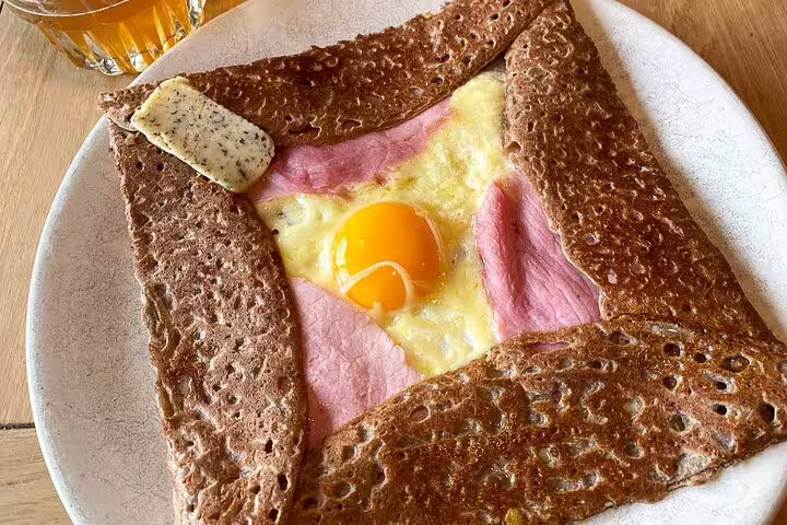 Traditional French galette complète with egg, ham and cheese on a white plate in Paris