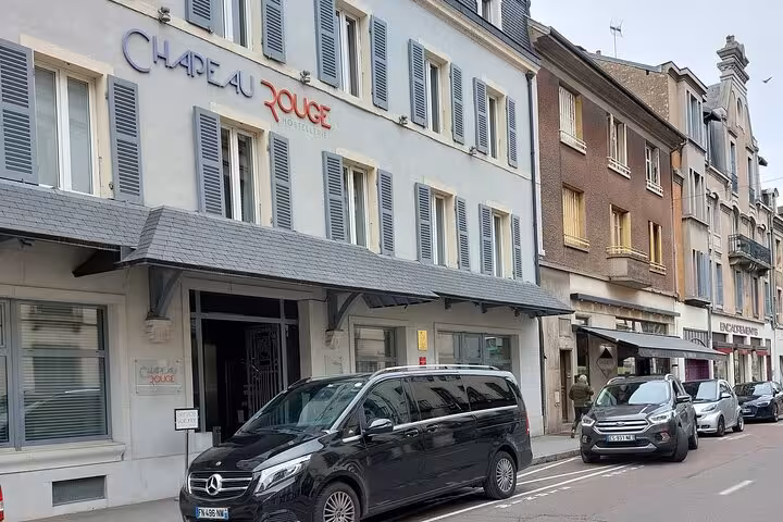 Black Mercedes van parked outside Chapeau Rouge hotel on a French city street