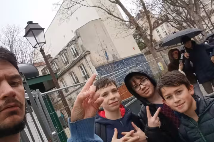 Adult and three teens posing on a rainy Paris street during a self-guided walking tour