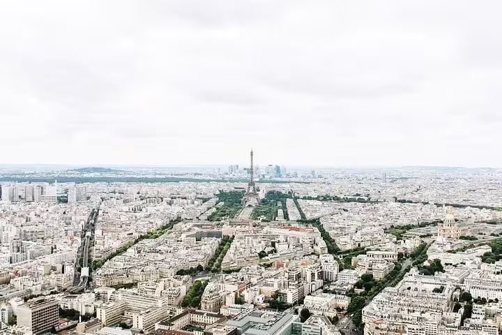 Aerial view of Paris skyline with Eiffel Tower at center, surrounded by Haussmann buildings