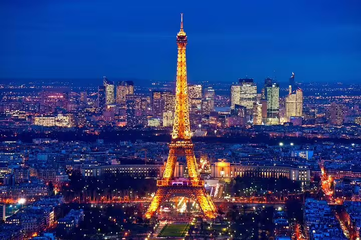 Eiffel Tower illuminated at night with golden lights against Paris city skyline